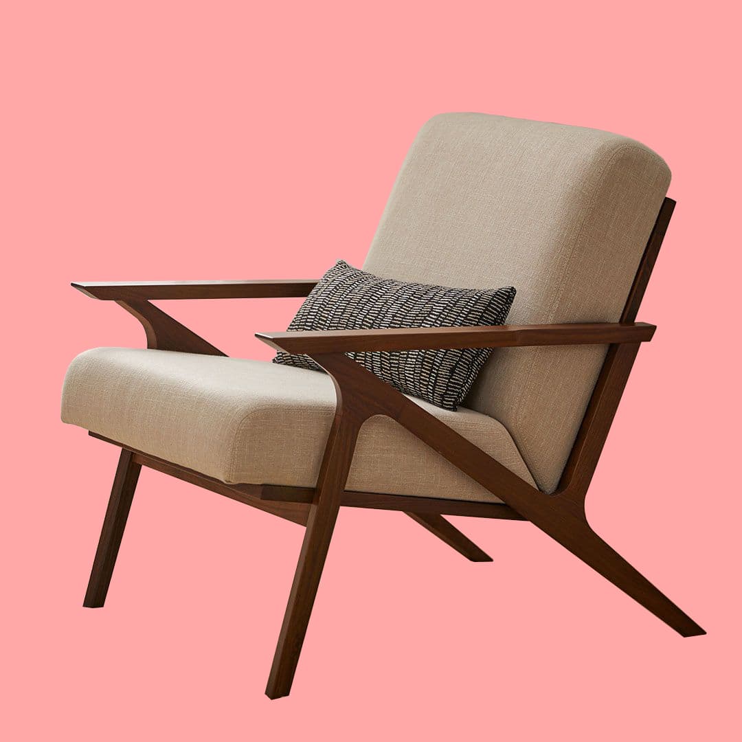 A mid-century modern armchair with a wooden frame and upholstered seat and back. The frame features elegantly curved arms and splayed legs. A small decorative pillow with a black and white geometric pattern is placed on the seat. — 3D model